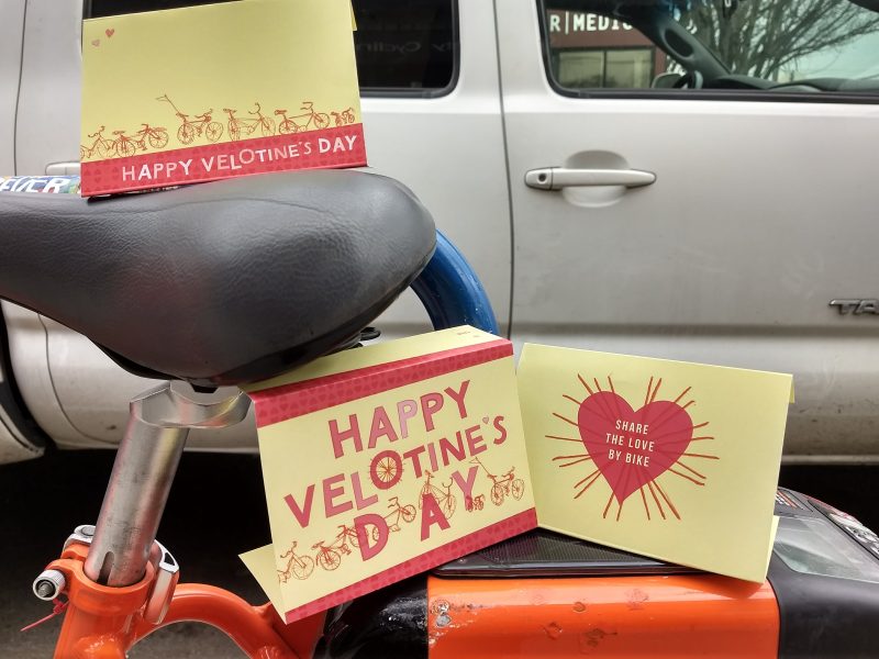 Photo of three yellow and red cards perched on a bike saddle and top bar. The cards say, "Happy Velotines Day"